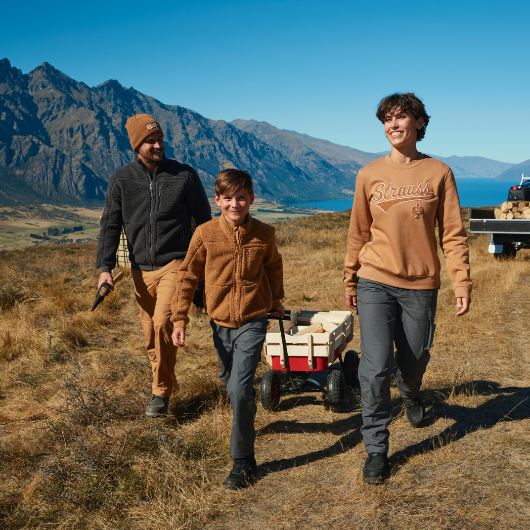 A man, a kid and a woman walking in front of a mountain landscape