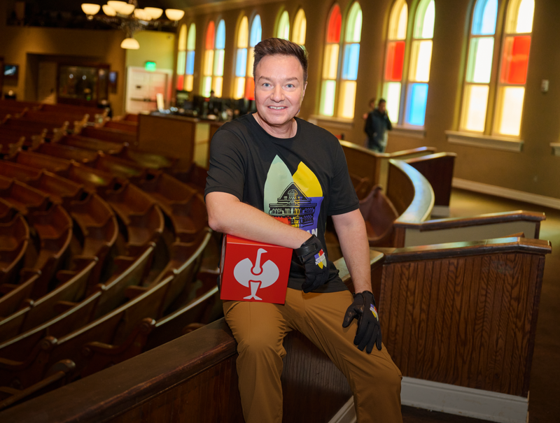 A picture of Henning Strauss at the Ryman Auditorium holding a red Strauss cube in his hands
