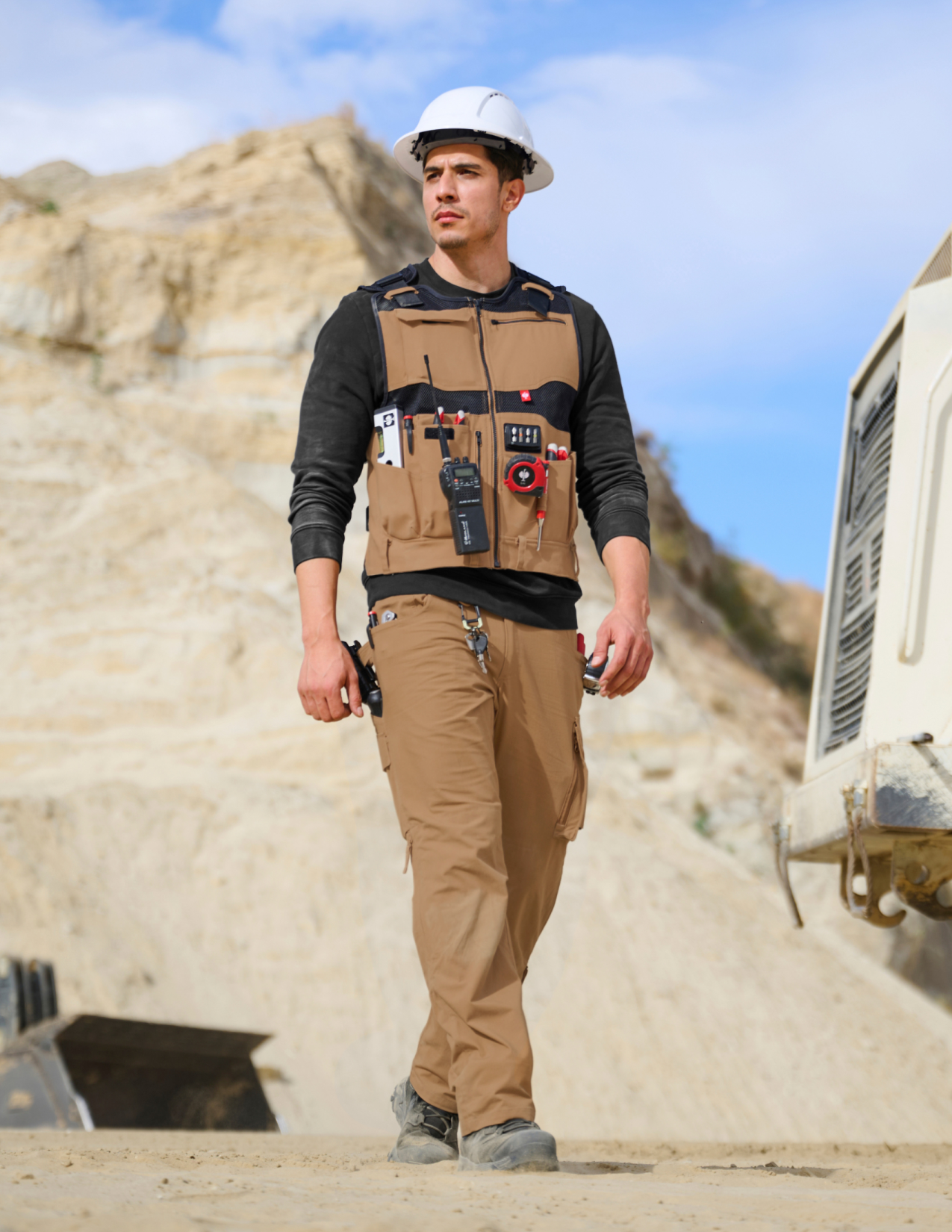 Person wearing a tool vest with various equipment in an outdoor setting