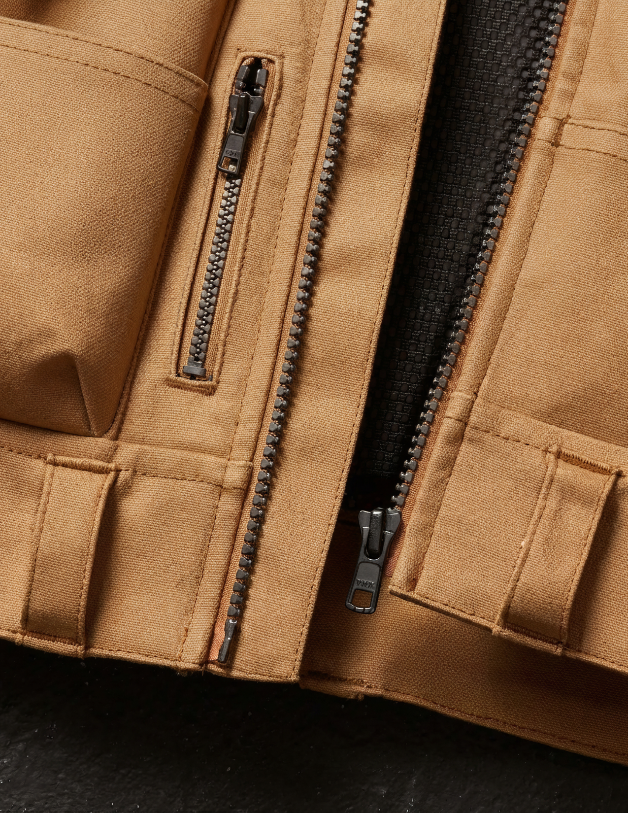 Close-up of a brown vest with zippers and pockets on a dark background
