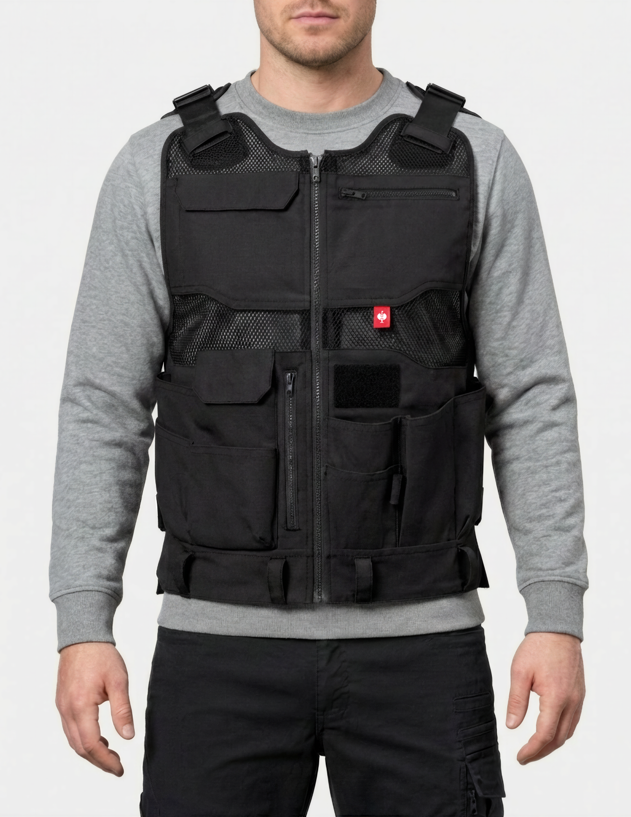 Person wearing a black tool vest over a gray sweater on a white background