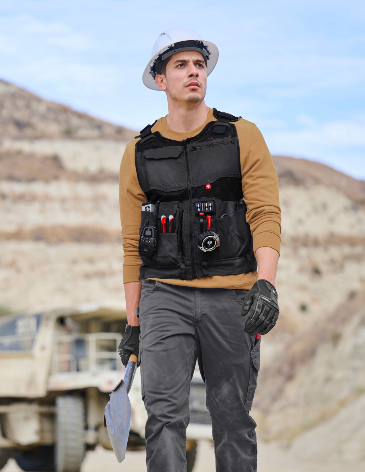 Person wearing a tool vest with various tools in a desert-like setting