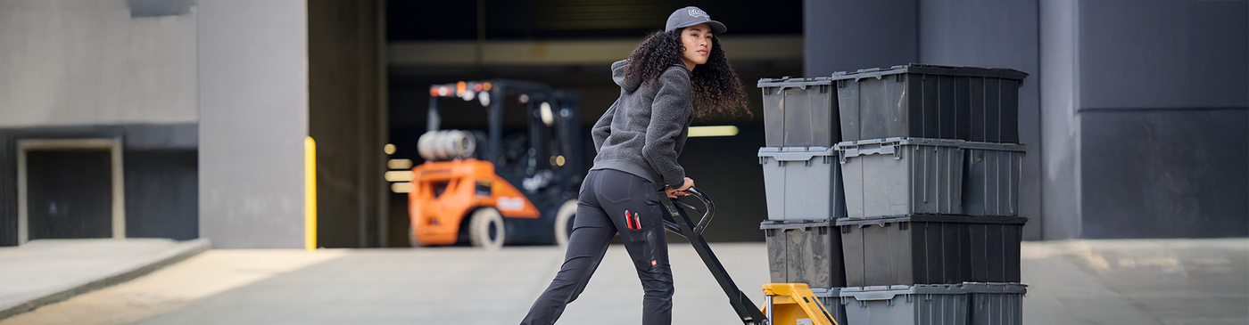 Person walking with black crates in an industrial setting