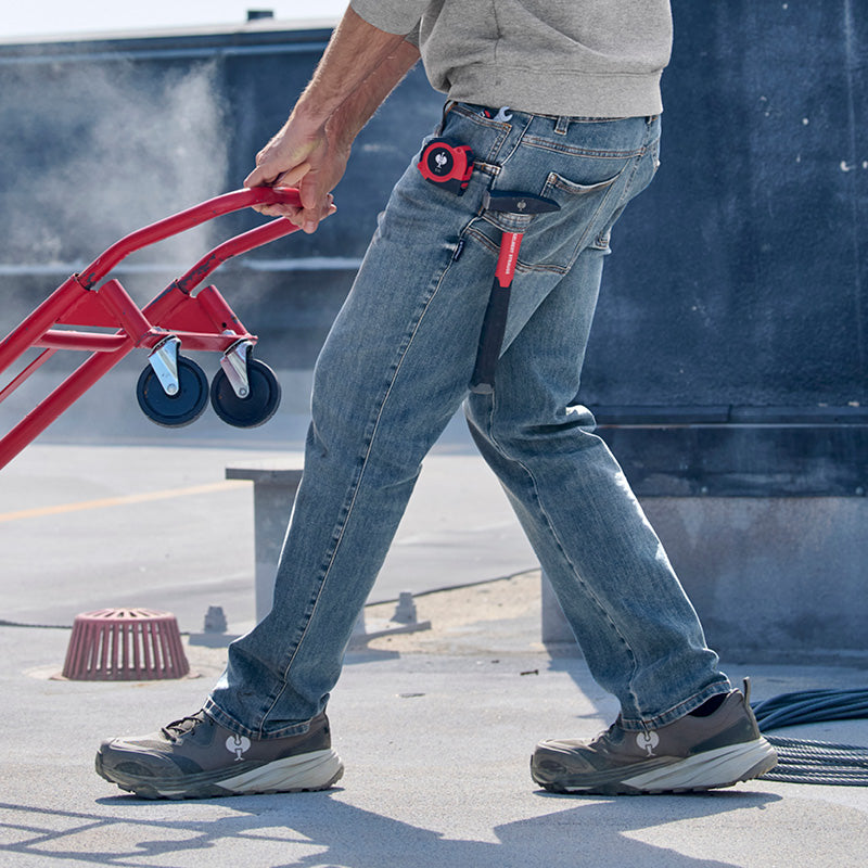 Person wearing Power Denim 5 pocket jeans and black shoes, holding a red dolly on a rooftop.