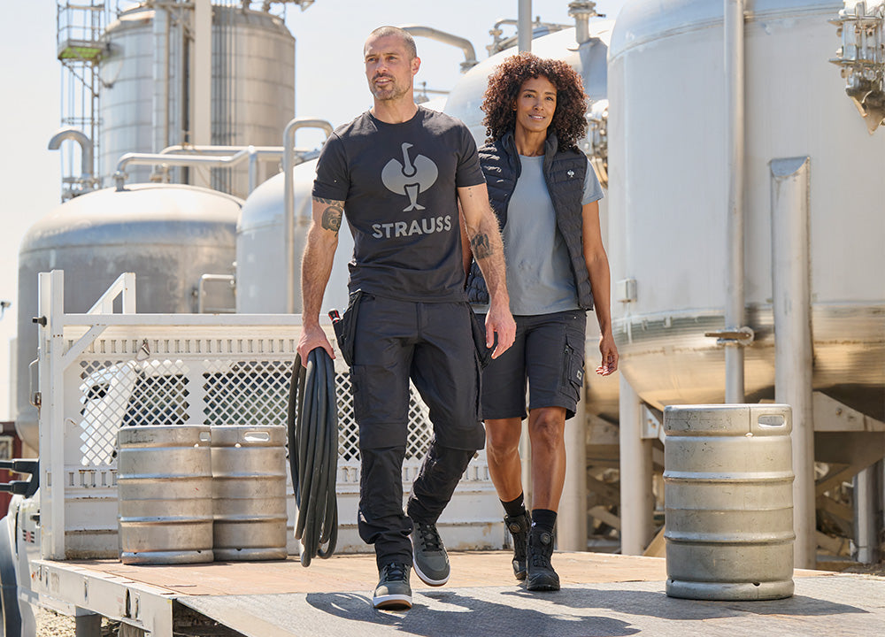 A man and woman walk around a factory in workwear from the e.s.Concrete collection.