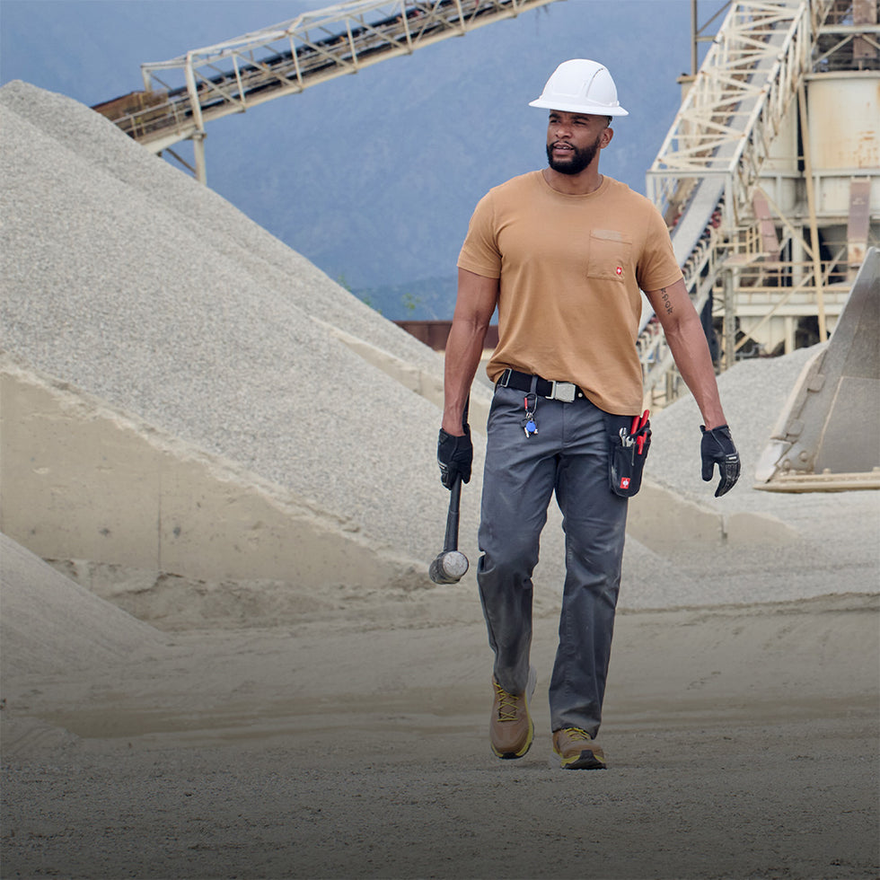 Man in work attire walking in an industrial setting wearing chinos.