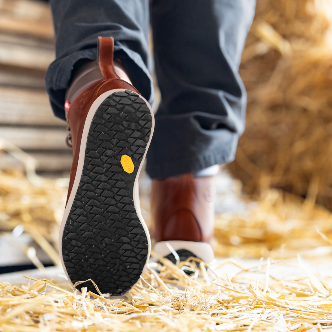 Close-up of brown leather boots with a yellow label on a black outsole