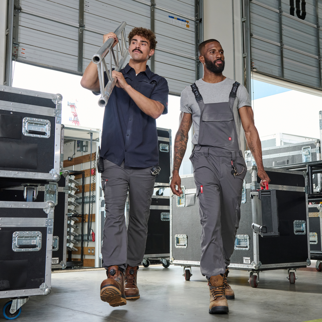 Two men in work attire walking through a warehouse with equipment.