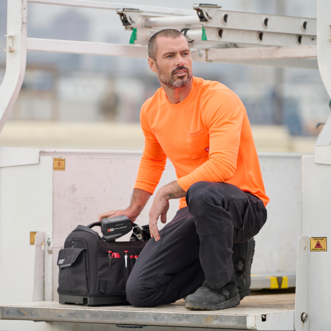 A man kneeling down and reaching into his tool bag
